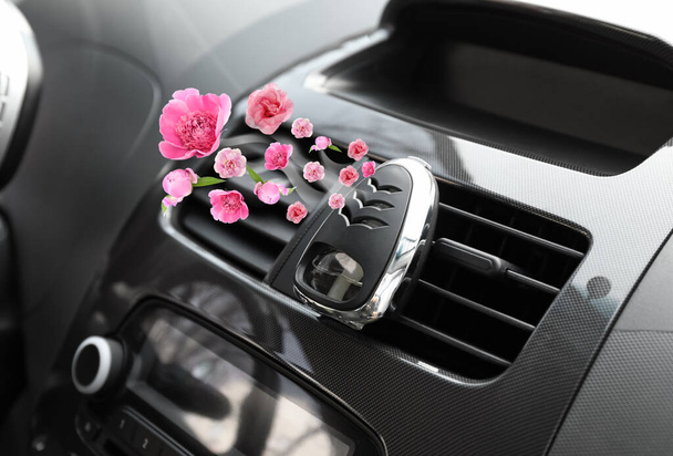 Aroma-Lufterfrischer mit fliegenden rosa Blüten im Autosalon - Foto, Bild