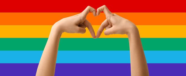 Woman making heart shape with her hands on rainbow background. LGBT concept - Photo, Image