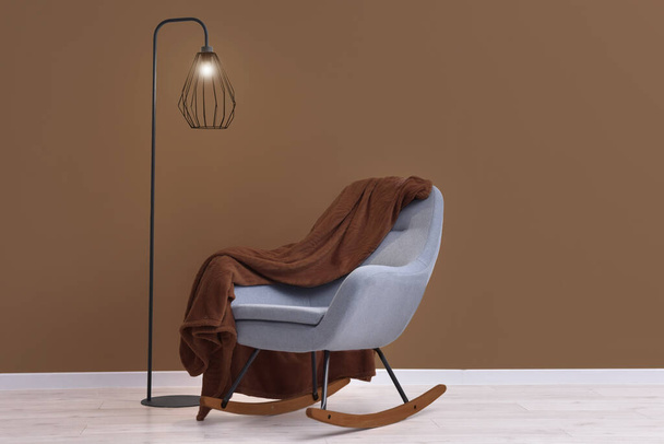 Sisustus moderni huone mukava nojatuoli ja lamppu lähellä ruskeaa seinää - Valokuva, kuva