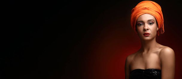 Portrait of beautiful African-American woman with head scarf on black background with space for text - Foto, Bild