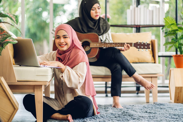 Jovens dois sorrindo feliz bela mulher muçulmana asiática relaxante usando computador portátil trabalhando e reunião analisando discutir estratégia com plano de projeto de inicialização e brainstorm em casa - Foto, Imagem