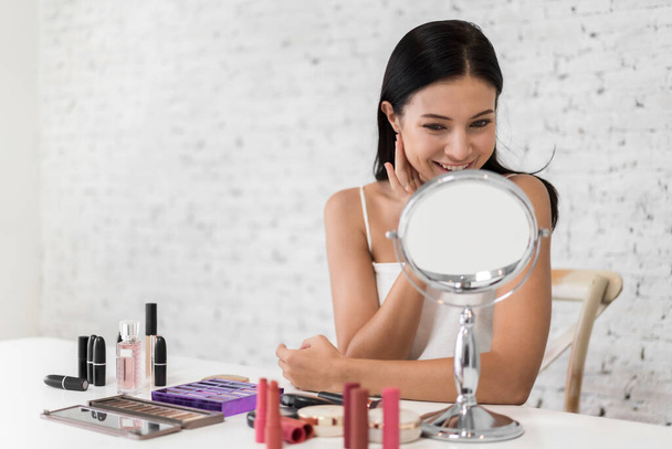 Smiling of young beautiful pretty woman clean fresh healthy white skin looking at mirror.girl touching on her face with hand and applying cream at home.spa and beauty concept - Photo, Image