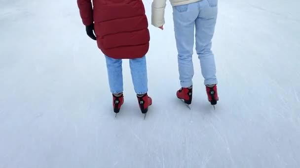 İki kişi kış günü açık havada buz pateni pistinde paten kayıyor. Buz pateni pistinde kayan insanlar. Bacaklar arkaya, buz pateni pistine. Kış tatili, aktiviteler, dinlenme, spor - Video, Çekim