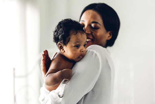 Portré élvezze boldog szerelem család afro-amerikai anya játszik imádnivaló kis afro-amerikai baba.Mom csók aranyos fiú pillanatok jó idő egy fehér hálószobában.Szerelem a fekete család - Fotó, kép