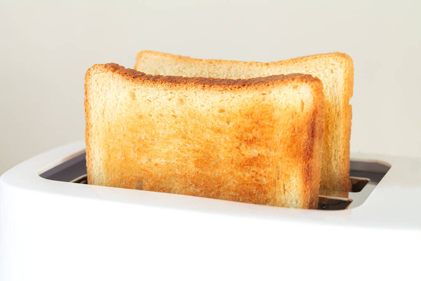 Modern beyaz ekmek kızartma makinesinde dilimlenmiş kızarmış ekmek. Mutfak masasının üstünde. - Fotoğraf, Görsel