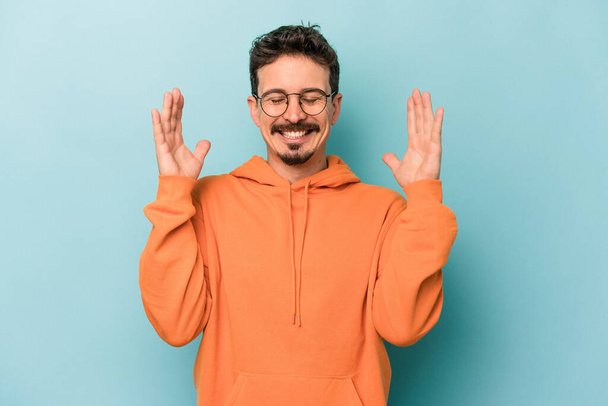 Young caucasian man isolated on blue background joyful laughing a lot. Happiness concept. - Photo, Image