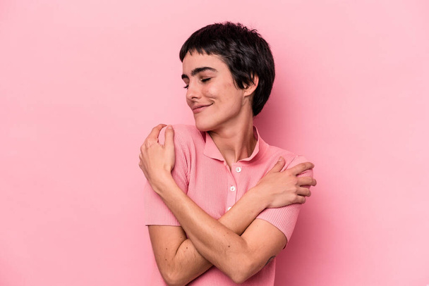 Young caucasian woman isolated on pink background hugs, smiling carefree and happy. - Photo, Image