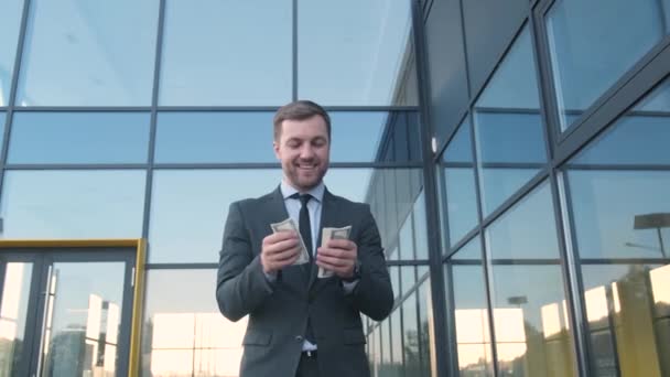 Счастливый успешный кавказский бородатый бизнесмен считает, выставляет напоказ, наличные на фоне современного офисного здания.  - Кадры, видео