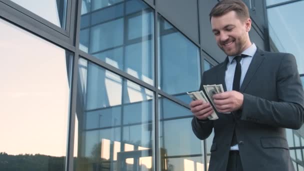 Радостный успешный человек в костюме считает деньги возле офиса,  - Кадры, видео