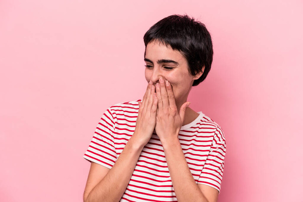 Mujer joven caucásica aislada sobre fondo rosa riendo de algo, cubriendo la boca con las manos. - Foto, imagen