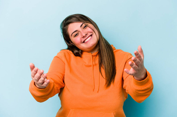 Young caucasian overweight woman isolated on blue background showing a welcome expression. - Foto, Imagem