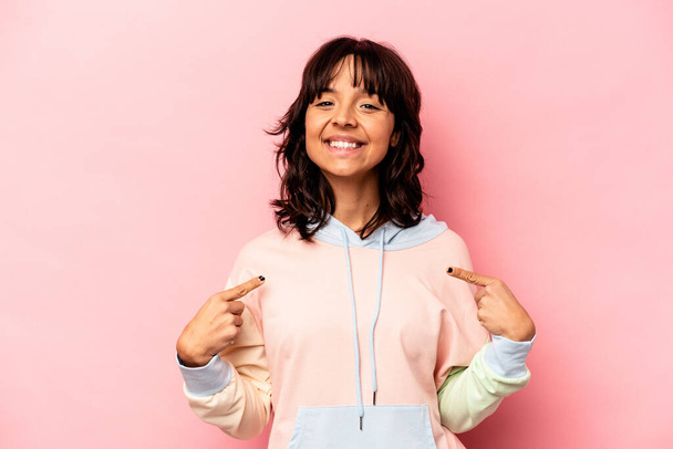 Young hispanic woman isolated on pink background points down with fingers, positive feeling. - Foto, imagen