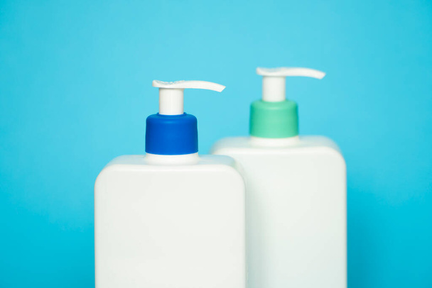 Shampoo or hair conditioner bottles with dispenser pump on blue background - 写真・画像