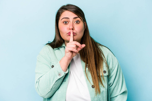 Young caucasian overweight woman isolated on blue background keeping a secret or asking for silence. - Photo, image