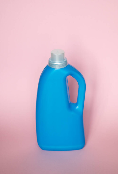 Blue plastic bottle stands on pink background. Conditioner or liquid powder for washing. Capacity with space for copying. Layout for logo application - Φωτογραφία, εικόνα