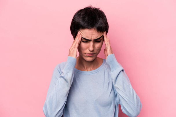 Young caucasian woman isolated on pink background having a head ache, touching front of the face. - Photo, Image