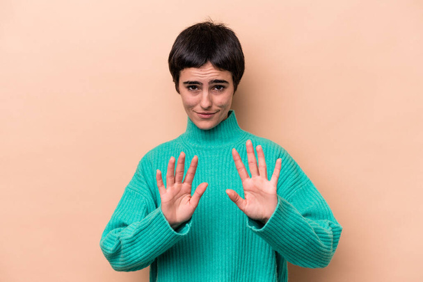 Young caucasian woman isolated on beige background rejecting someone showing a gesture of disgust. - Photo, Image