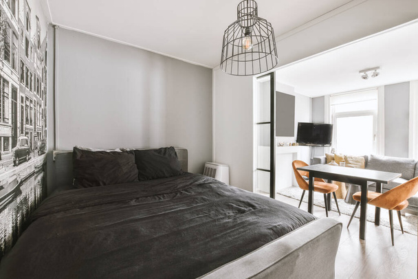 Design intérieur minimaliste de petite chambre à coucher avec lit doux placé dans un coin et table en bois avec éclairage de la lampe - Photo, image