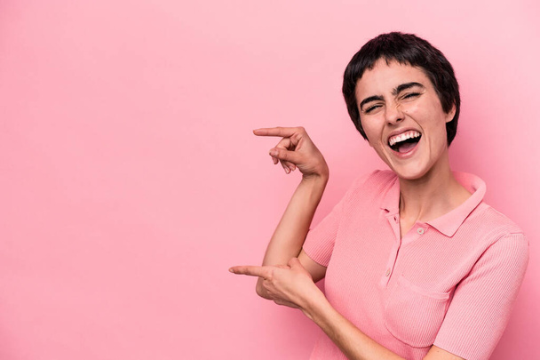 Young caucasian woman isolated on pink background excited pointing with forefingers away. - Zdjęcie, obraz