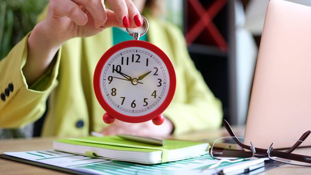 Деловая женщина держит будильник два часа в офисе. Перерыв и обед в бизнес-концепции - Фото, изображение