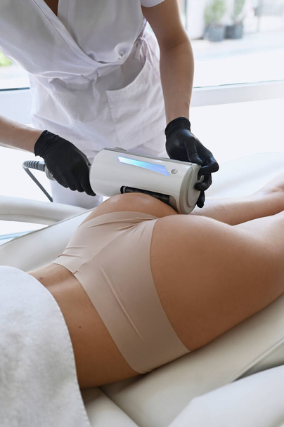 Beautiful woman enjoys buttocks massage with endosphere machine for anti-cellulite and body correction - Fotó, kép