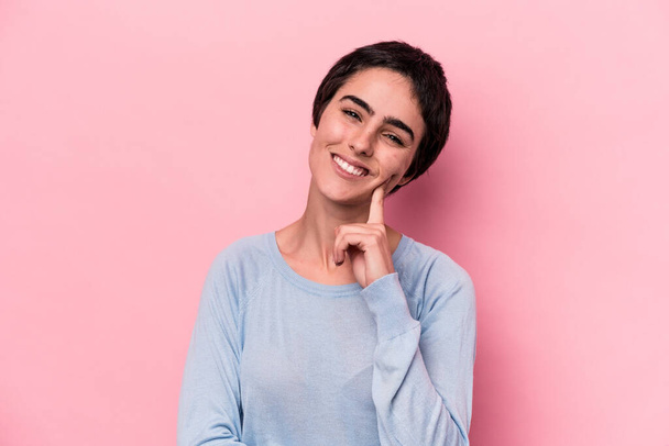 Young caucasian woman isolated on pink background smiling happy and confident, touching chin with hand. - Photo, Image