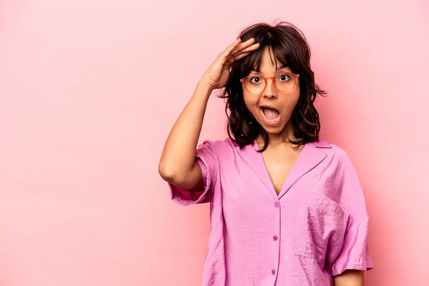 Young hispanic woman isolated on pink background shouts loud, keeps eyes opened and hands tense. - Photo, Image