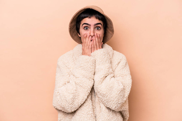 Young caucasian woman isolated on beige background shocked, covering mouth with hands, anxious to discover something new. - Photo, image
