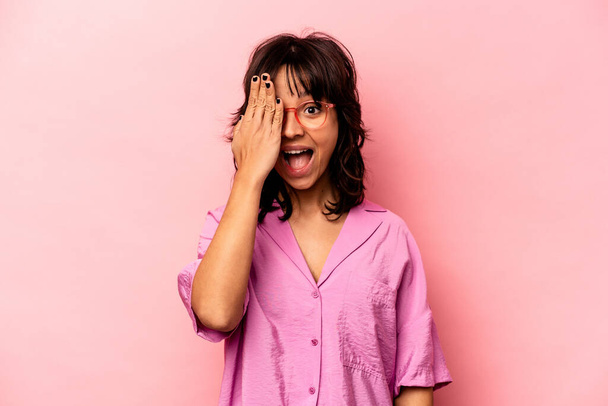 Young hispanic woman isolated on pink background having fun covering half of face with palm. - Zdjęcie, obraz