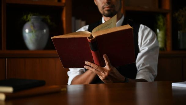 Профессиональный и умный азиатский бизнесмен или мужчина-менеджер, читающий книгу или учебник на своем рабочем столе. обрезанное изображение - Фото, изображение