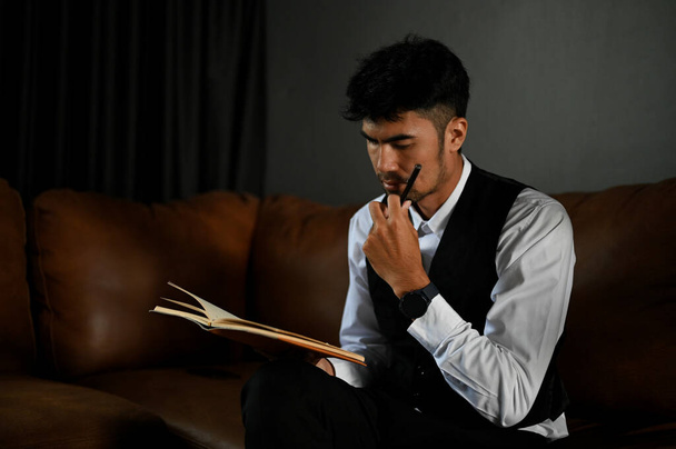 Професійний дорослий азіатський бізнесмен зосередився на читанні книжки, думаючи і плануючи бізнес-стратегію в офісі.. - Фото, зображення