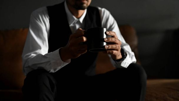 Empresário asiático bem sucedido e profissional, CEO masculino, chefe masculino ou gerente executivo em processo formal senta-se no sofá com seu café preto. Close-up e cortado  - Foto, Imagem