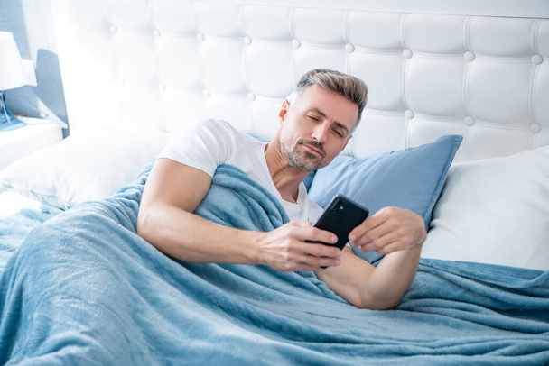 mature man in bed chatting on phone. - Φωτογραφία, εικόνα