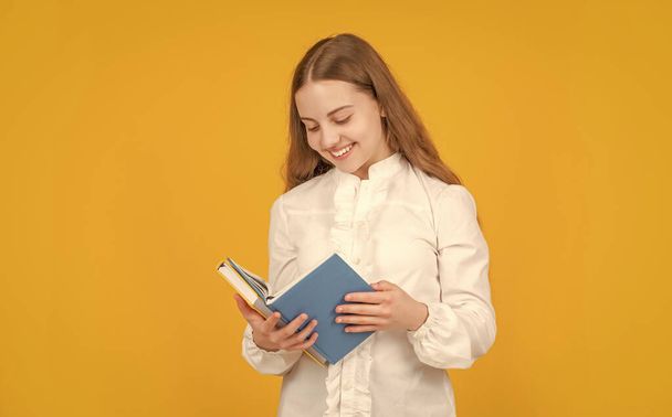 happy teen girl in white shirt ready to study do homework read book on yellow background, reader. - Φωτογραφία, εικόνα