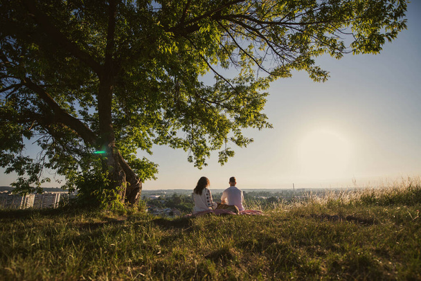 Mladý pár se dívá na východ slunce nad horou. Svatba objímání pod stromem na poli na Ukrajině. - Fotografie, Obrázek