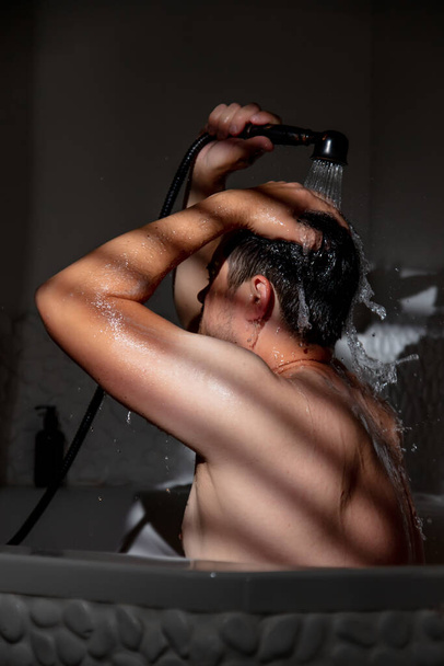 Adam küvette duşun altında yıkanır. - Fotoğraf, Görsel