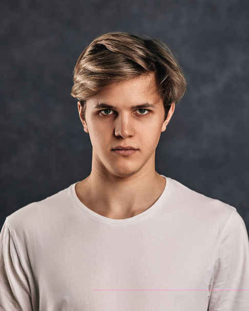 young man frowning on gray background. Human emotions, facial expressions - Foto, Imagem