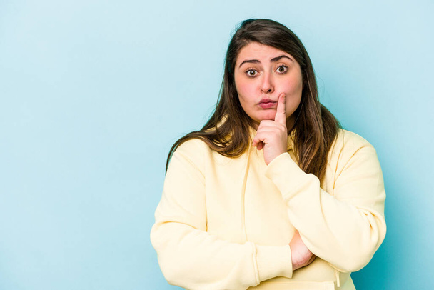 Young caucasian overweight woman isolated on blue background looking sideways with doubtful and skeptical expression. - Foto, Bild