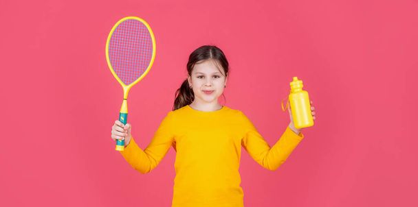cheerful kid hold tennis racket and water bottle on pink background. - Photo, Image