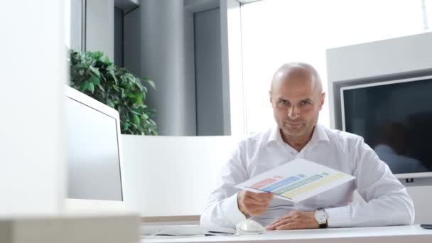 Důvěrně pohledný zaměstnanec banky středního věku, profesionální finanční manažer demonstruje bankovní úrokovou sazbu. Video 4K - Záběry, video