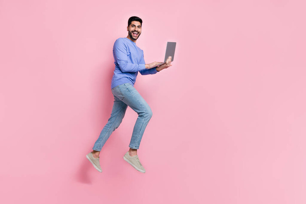 Full length photo of excited sweet man wear long sleeve shirt charring modern gadget jumping high isolated pink color background. - Фото, изображение