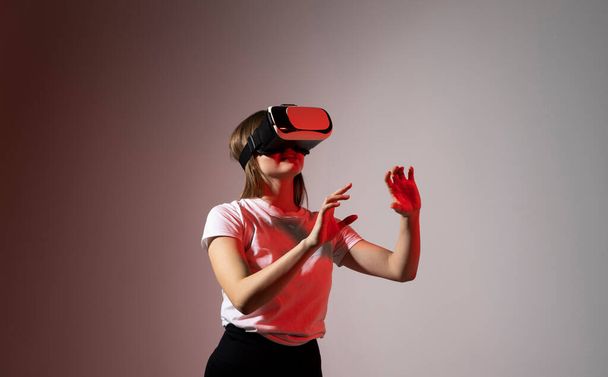 Young woman working in VR goggles on a grey background. Modern architect using virtual reality glasses at workplace. Designer working in augmented reality vr studio - Фото, зображення