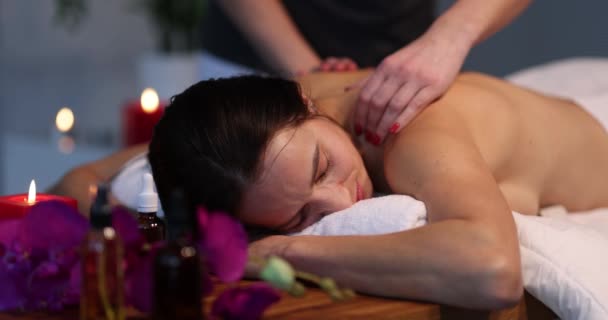 Beautiful young woman enjoying a massage at spa. Masseuse services and therapeutic back massage concept - Footage, Video