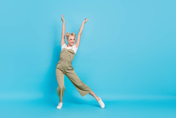 Full length photo of sweet blond lady dance wear t-shirt overall sneakers isolated on blue background. - Fotoğraf, Görsel