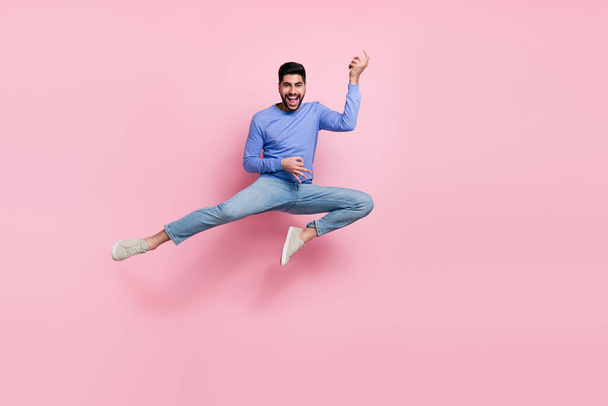 Full length photo of funny pretty man wear long sleeve shirt jumping high playing guitar isolated pink color background. - Photo, image