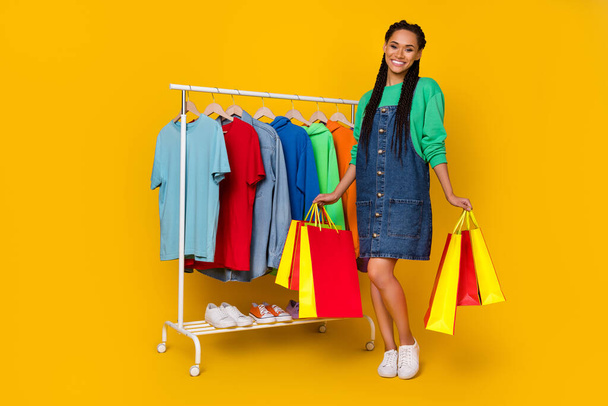 Full body portrait of cheerful charming person hold packages choose variety isolated on yellow color background. - Photo, Image