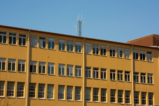 Παλιό κίτρινο βιομηχανικό κτίριο. Κεραίες επικοινωνιών στην οροφή. - Φωτογραφία, εικόνα