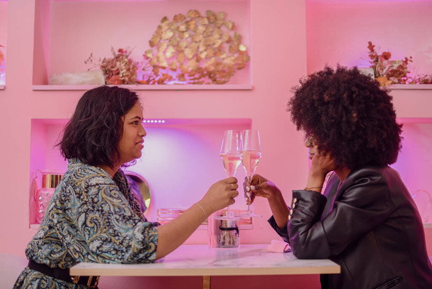 LGBT. Lesbian couple together concept. Couple of young asian woman and african woman drinking and having fun in a bar. - Photo, image