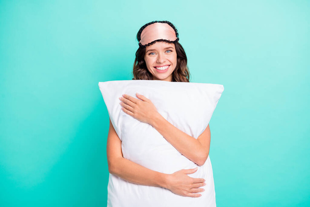 Photo of sweet charming young woman sleepwear embracing white big pillow isolated turquoise color background. - Foto, Imagen