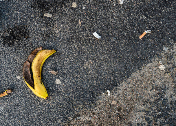 Banana peel, snuff, cigarette butt and other garbage on asphalt. - Foto, Bild